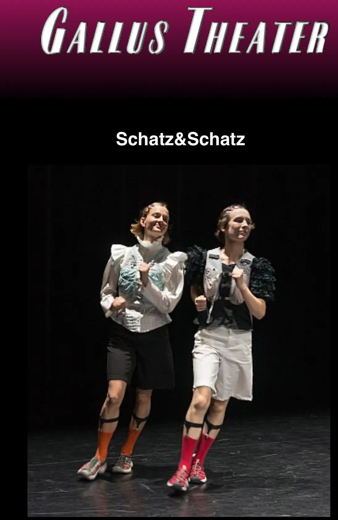 Alexandra Entenmann und Fine Kroke walken in Kostümen mit Rüschenärmeln, Shorts und bunten Kniestrümpfen nebeneinander über eine dunkle Bühne